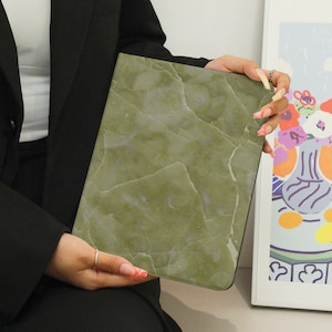 May include: A green marble-patterned clutch purse with a smooth, textured surface.
