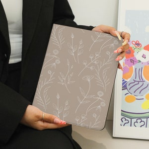 May include: A light brown notebook cover with a white floral design. The cover has a subtle texture and a minimalist aesthetic.