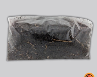 May include: A clear plastic bag filled with dark brown soil. The soil appears to contain small pieces of straw and other organic matter. The bag is sealed and sits against a light gray background.