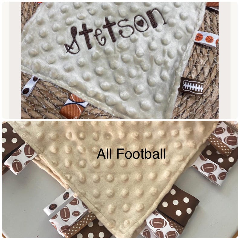 May include: A cream-coloured minky fabric security blanket with a raised dot texture. The top section features the embroidered name Stetson in brown thread. The edges are adorned with various ribbons featuring football and basketball patterns.