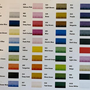 May include: A colour reference chart featuring a grid of numbered thread swatches. Each entry displays a unique numerical code, a colour name, and a corresponding rectangular sample of thread colour, ranging from white and silver to various blues, greens, and reds.