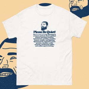 以下が含まれることがあります： 「Please Be Quiet!」の文字と、ひげを生やした男性のグラフィックがプリントされた白いTシャツ。テキストには、モーニングルーティン、テストステロン、クリプトなどに関するポッドキャストの詳細が記載されています。柔らかく快適な素材で作られています。