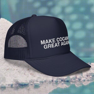 May include: A navy blue trucker hat with a white mesh back. The hat has white embroidered text that reads "MAKE COCAIN GREAT AGAIN".