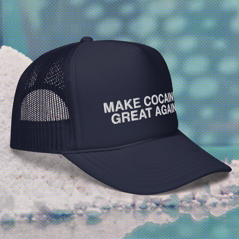 May include: A navy blue trucker hat with a white mesh back. The hat has white embroidered text that reads "MAKE COCAIN GREAT AGAIN".