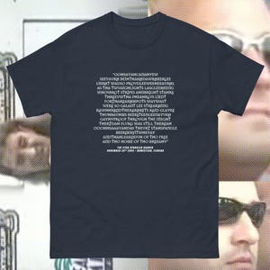 Pode incluir: Uma camiseta azul marinho com texto branco que diz "OOHSAYAНСАПАНYEW SEEYAURH BEIHTHARHDAWRHZERLEE LIERHT WADSO PROUDLEEWEEHEEAURHL AS THA TWUAIGHLIGHTS LASGLEEMEENG WHOSBROT STRIPES AHIIBRIGHT STAHRS THREEUWTHA PHEAHRLUS LIEDT FORTHAREARHIMPOTS WAYWAST WERE SO GALANT LEE STREARMING RAWWHHRRLIDTHERARHKETS RAID GLAYRE THUHBAUHMS BEERSTEENGEE&Pi;AYURH GAYHVPROOF THROUGH THE ПЕСНТ THER DAH FLURG WAS STILL THEREAH OOOHHSARAYAHDAS THEURT STAHSPANGLE BEERDERYITWHEYAY ANDTHAHLEARIDUH OF THO FREE AND THO HOME OF THO BREEAHV" THE STAR SPANGLER BANNER NOVEMBER 20 2005-NOMISTEAR FLORIDA"