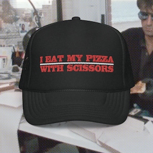 Könnte beinhalten: Schwarze Trucker-Kappe mit einem roten gestickten Spruch "I EAT MY PIZZA WITH SCISSORS" auf der Vorderseite.