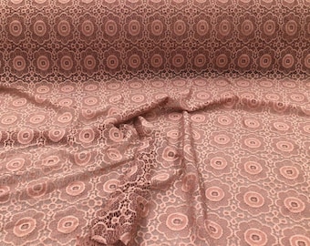 May include: A close-up of a dusty rose lace fabric with a delicate floral pattern. The fabric is soft and flowing, with a subtle sheen.