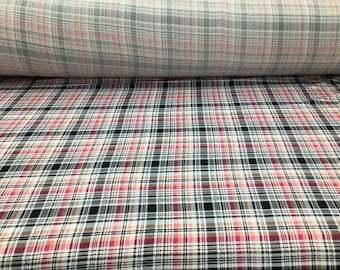 May include: A close-up of a plaid fabric with a black, white, pink, and brown pattern. The fabric is folded in half, showing the pattern on both sides.