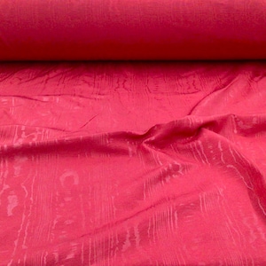 May include: A close-up of a pink fabric with a woodgrain pattern. The fabric is soft and has a subtle sheen.
