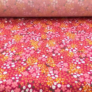May include: Red fabric with a small-scale floral print in shades of pink, white, and orange.