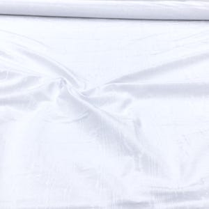 May include: White satin fabric with a smooth, silky texture. The fabric is folded and draped, showing its luxurious sheen.