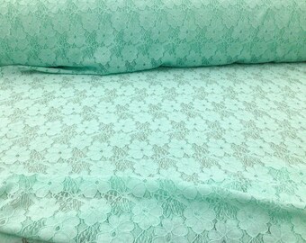May include: Mint green lace fabric with a delicate floral pattern. The fabric is soft and sheer, making it perfect for a variety of crafting projects.