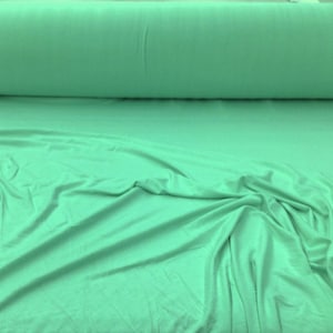 May include: A roll of soft, light green fabric. The fabric is smooth and has a slight sheen.