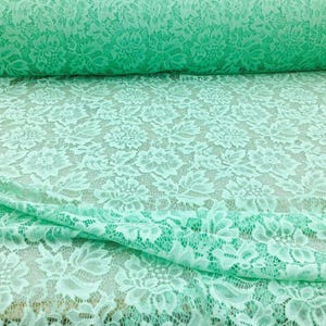 May include: Mint green lace fabric with a delicate floral pattern. The lace is soft and sheer, making it perfect for a variety of crafting projects.
