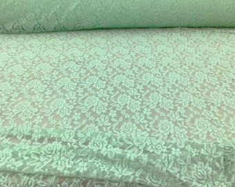 May include: Pale green floral lace fabric with a delicate pattern of small roses and leaves. The lace is soft and sheer, making it perfect for a variety of crafting projects.