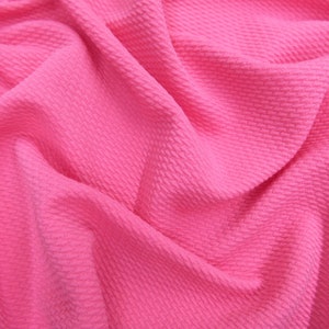 May include: Close-up of a pink textured fabric with a crinkled and folded appearance.