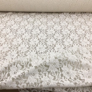 May include: White floral lace fabric with a delicate pattern. The lace is soft and sheer, making it perfect for a variety of crafting projects.