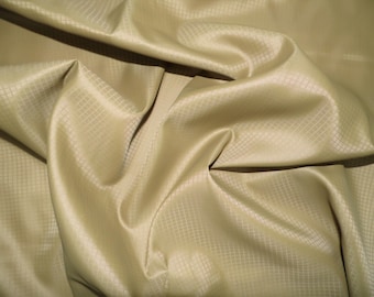May include: A close-up of a beige fabric with a subtle grid pattern. The fabric is soft and has a slight sheen.
