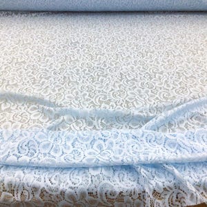 May include: Light blue lace fabric with a delicate floral pattern. The lace is soft and sheer, making it perfect for a variety of crafting projects.