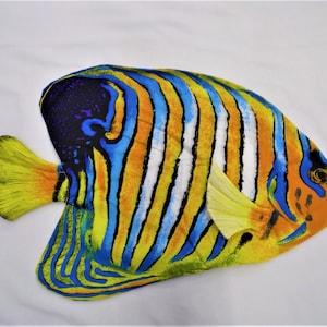 May include: A colorful, yellow, blue, and white fish with black stripes. The fish is a realistic, flat, decorative piece.