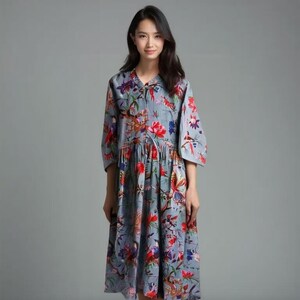 May include: A gray midi dress with a floral print featuring birds and flowers. The dress has a V-neckline and 3/4 sleeves.