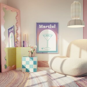 Puede incluir: Interior de una habitación con un gran espejo rosa con bordes ondulados, un cuadro enmarcado con la palabra "Martini" y un sillón crema. La obra de arte muestra una copa de martini. Elementos decorativos incluyen velas, un cubo a cuadros y una alfombra estampada. Una lámpara colgante ilumina el espacio.