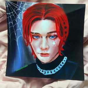 Puede incluir: Una ilustración digital de una persona con cabello rojo, ojos azules y un collar de cadena plateada. La persona tiene múltiples piercings en la cara y una araña en la mejilla. El fondo es azul oscuro con una telaraña blanca.