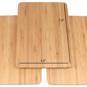 Op de afbeelding: Drie houten snijplanken van bamboe, op elkaar gestapeld. De bovenste plank is 7,9 inch lang en 5,5 inch breed.