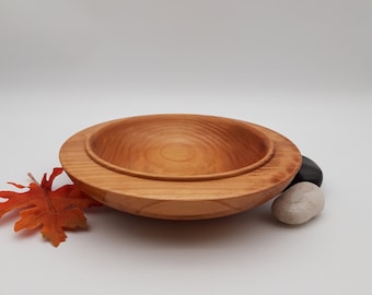 May include: A wooden bowl with a natural finish. The bowl is made of two pieces, with the top piece fitting inside the bottom piece. The bowl is sitting on a white surface with two small stones.