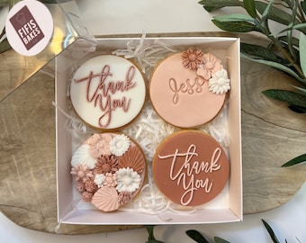 Può includere: Una scatola di quattro biscotti decorati. Due biscotti dicono "Thank You" in un font corsivo. Un biscotto è decorato con il nome "Jess". Il quarto biscotto è decorato con fiori. I biscotti sono in una scatola bianca con imbottitura di carta.