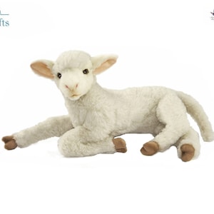 May include: A plush, cream-colored lamb toy with a soft, textured coat. The lamb is lying down with its front legs extended and its head raised. It has brown hooves and ears, and dark eyes. The toy is designed to look realistic.
