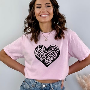 May include: A pink t-shirt with a black leopard print heart design.