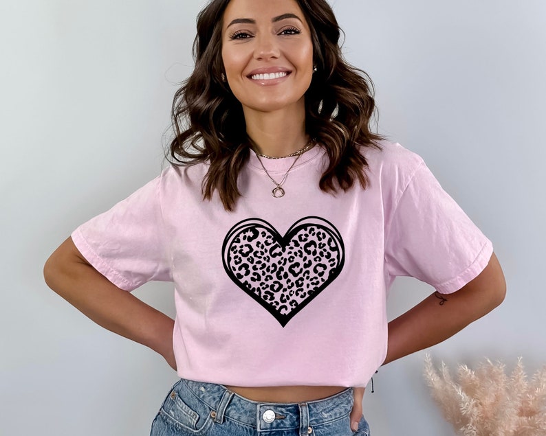 May include: A pink t-shirt with a black leopard print heart design.