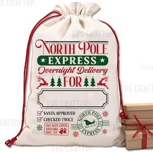 Puede incluir: Una bolsa de lona blanca con ribetes rojos y el texto "North Pole Express Overnight Delivery For" en verde y rojo. La bolsa tiene una cinta roja y una etiqueta aprobada por Santa Claus con una marca de verificaci&oacute;n. La bolsa est&aacute; sentada en una mesa con una pila de cajas de regalo marrones envueltas con una cinta roja.