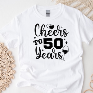 May include: White t-shirt with black text that reads "Cheers to 50 Years" with two hearts and a wine glass graphic.