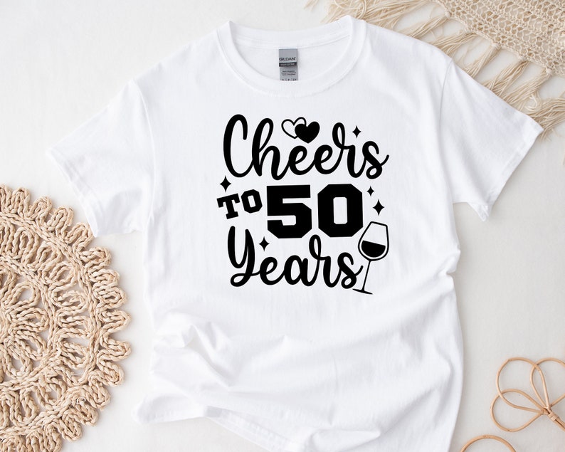 May include: White t-shirt with black text that reads "Cheers to 50 Years" with two hearts and a wine glass graphic.