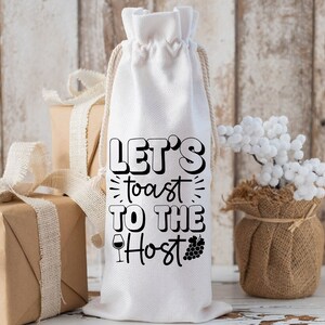 May include: White fabric wine bottle bag with black text that reads "Let's toast to the Host". The bag has a drawstring closure and is decorated with a small wine glass and grapes.