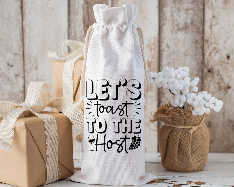 May include: White fabric wine bottle bag with black text that reads "Let's toast to the Host". The bag has a drawstring closure and is decorated with a small wine glass and grapes.