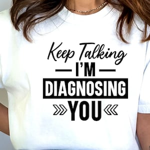 May include: White t-shirt with black text that reads "Keep Talking - I'm Diagnosing You" with arrows pointing in and out.