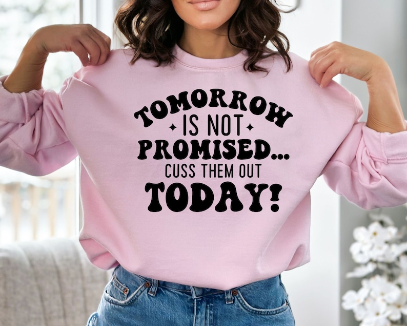 May include: Pink sweatshirt with the text "Tomorrow is not promised... Cuss them out today!" in black.
