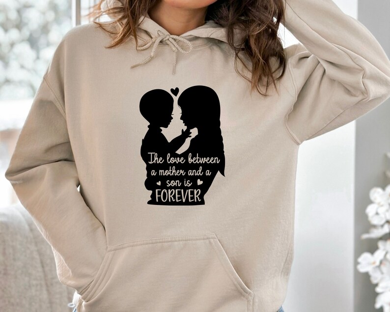 May include: A beige hoodie with a black silhouette of a mother and son hugging. The text "The love between a mother and a son is FOREVER" is printed below the silhouette.