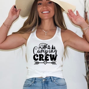 May include: A white tank top with a black graphic that says "Camping Crew" with a camper, campfire, and trees. The graphic also includes an arrow and a heart.