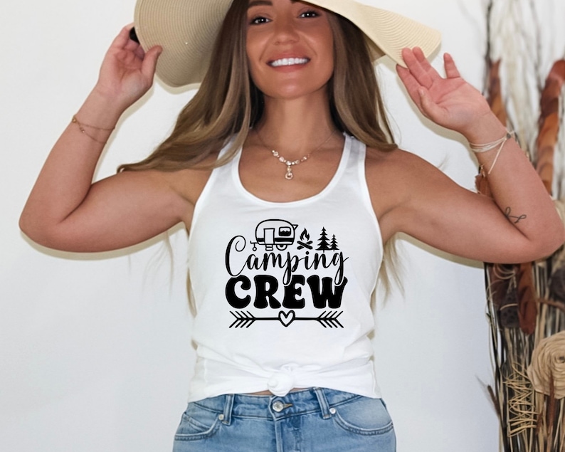 May include: A white tank top with a black graphic that says "Camping Crew" with a camper, campfire, and trees. The graphic also includes an arrow and a heart.