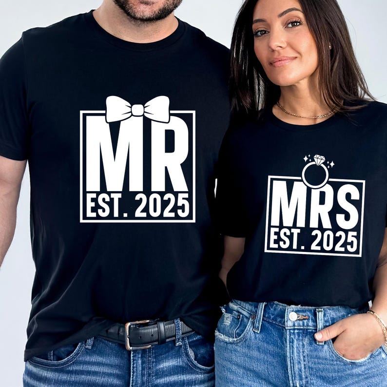 K&ouml;nnte beinhalten: Zwei passende schwarze T-Shirts mit wei&szlig;em Text. Eines zeigt "MR EST. 2025" mit einer Fliege. Das andere zeigt "MRS EST. 2025" mit einem Diamantring. Beide Designs sind in wei&szlig;en K&auml;stchen.