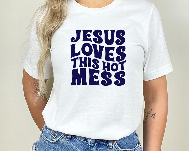 K&ouml;nnte beinhalten: Wei&szlig;es T-Shirt mit einem marineblauen Aufdruck, auf dem "Jesus Loves This Hot Mess" steht.