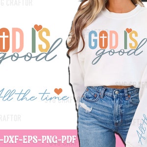 May include: A white sweatshirt with the text "GOD IS good" in colorful letters with a cross and a heart. The text "All the time" is written in blue below the main text. The sweatshirt is being worn by a person with long brown hair.