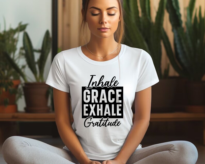May include: White t-shirt with black text that reads "Inhale Grace Exhale Gratitude".