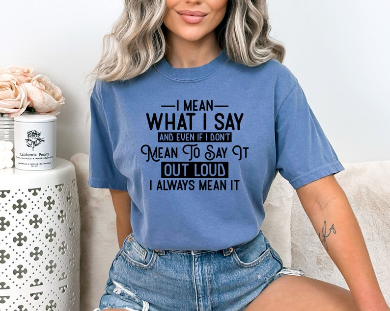 May include: A blue t-shirt with the text "I mean what I say and even if I don't mean to say it out loud I always mean it" printed in black.