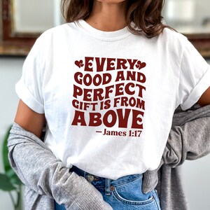 K&ouml;nnte beinhalten: Wei&szlig;es T-Shirt mit einer roten Grafik, auf der "Every good and perfect gift is from above - James 1:17" steht.