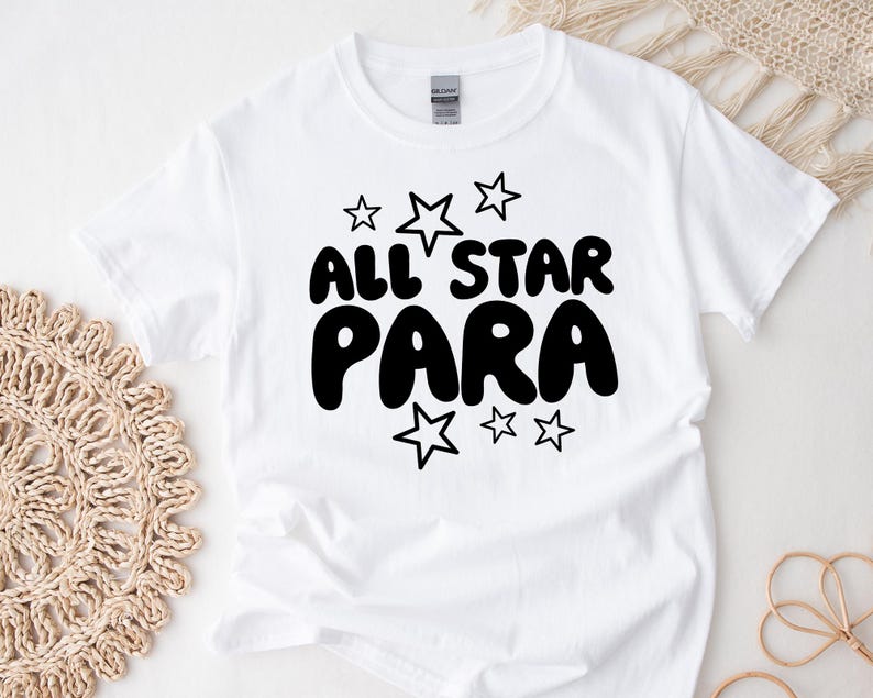 May include: White t-shirt with black text that reads "All Star Para" with stars around the text.